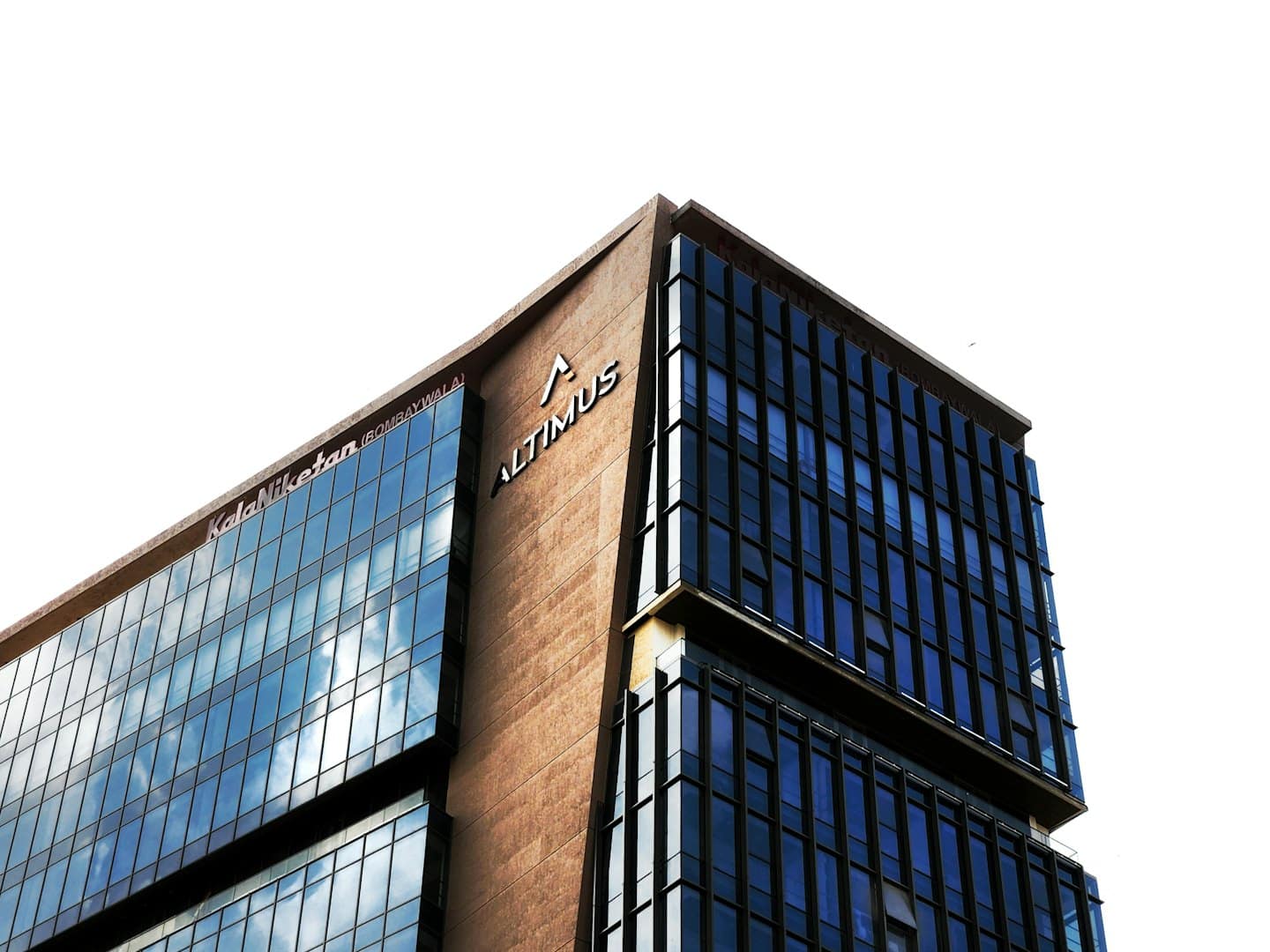 Modern office building corner with blue glass and textured walls.