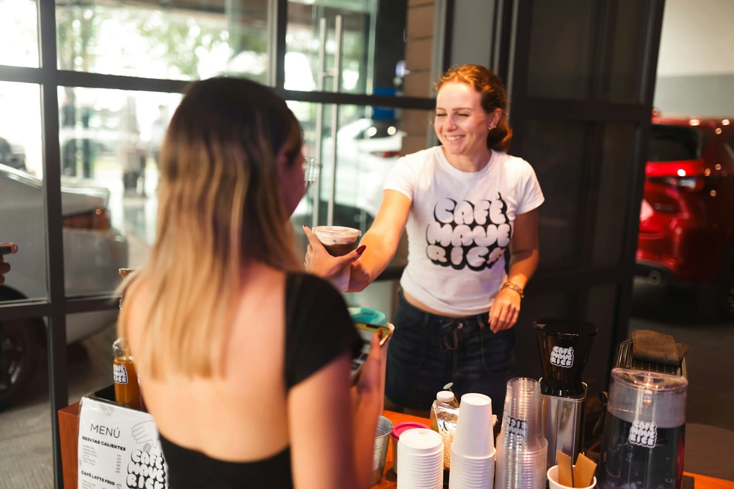 Barista serving a coffee to a customer at a mobile stand.