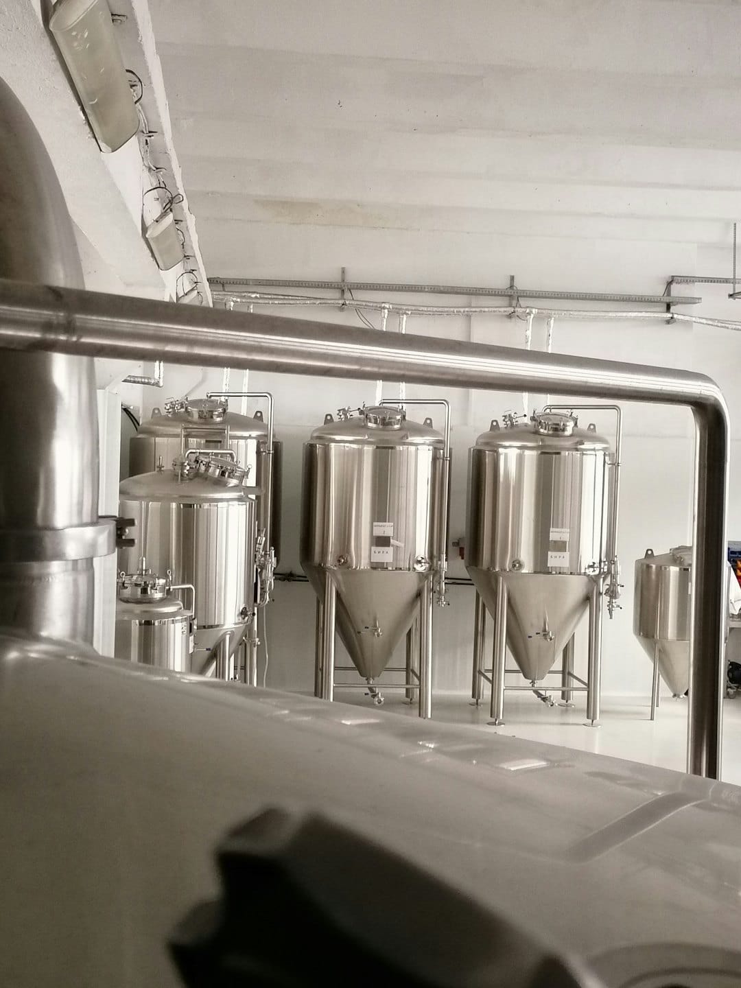 Stainless steel fermentation tanks in a bright brewery production area.
